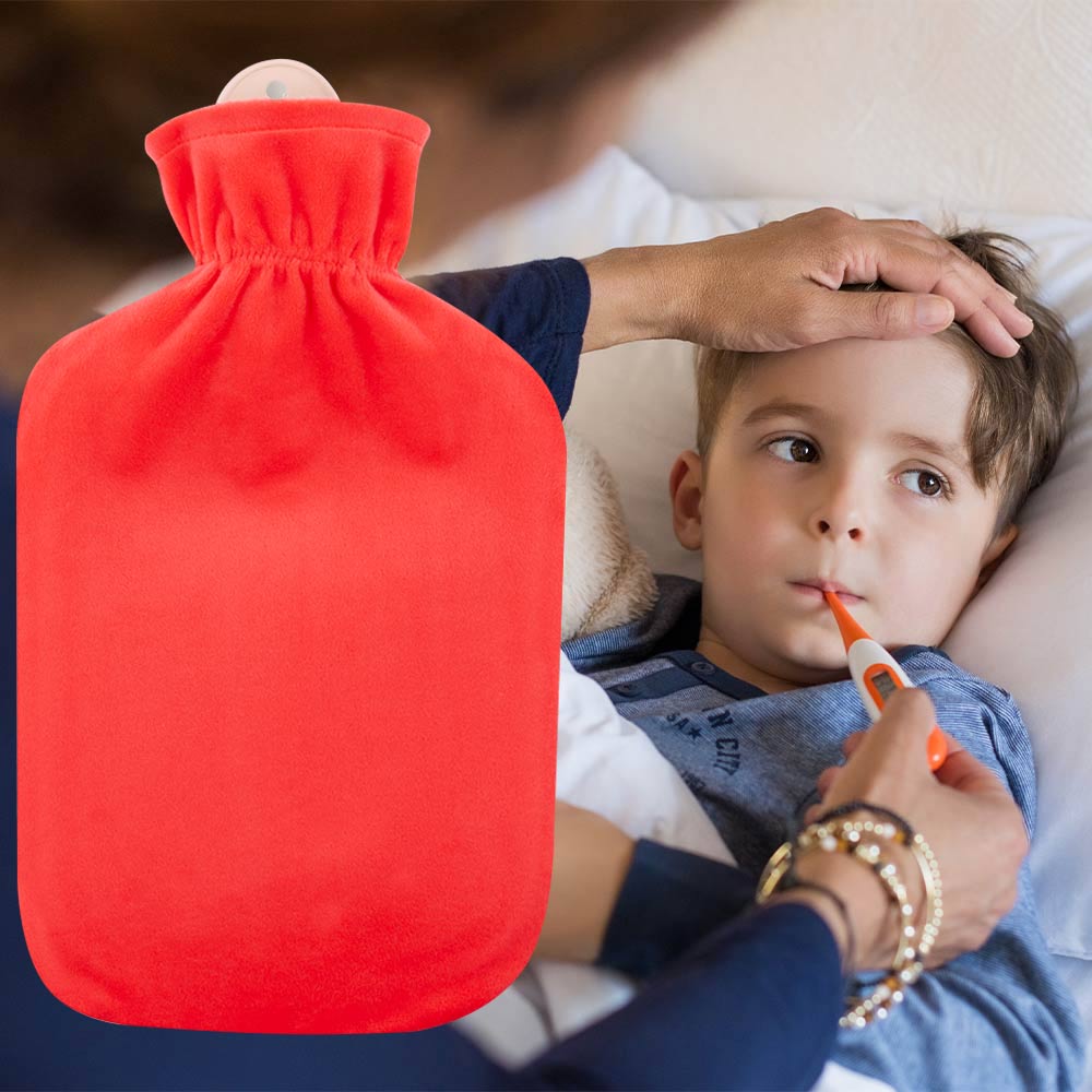 2‑Liter‑Wärmflasche in Koralle mit Flauschbezug, neben einem Kind im Bett