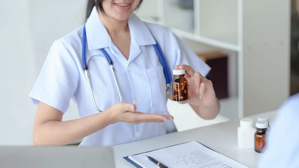 A young doctor presenting a bottle of pills at her desk