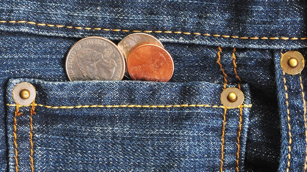 A pair of jeans with nickel buttons and some old coins