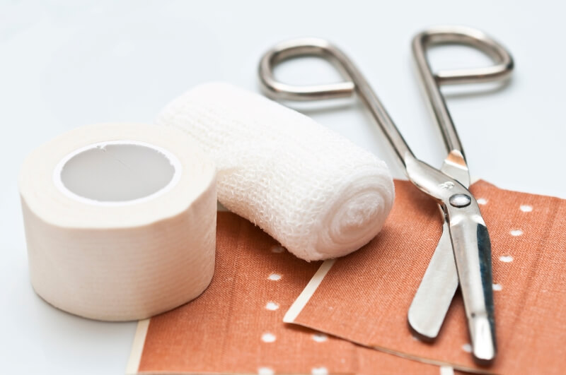 The picture shows different types of bandage material and a pair of bandage scissors - buy bandage material now!